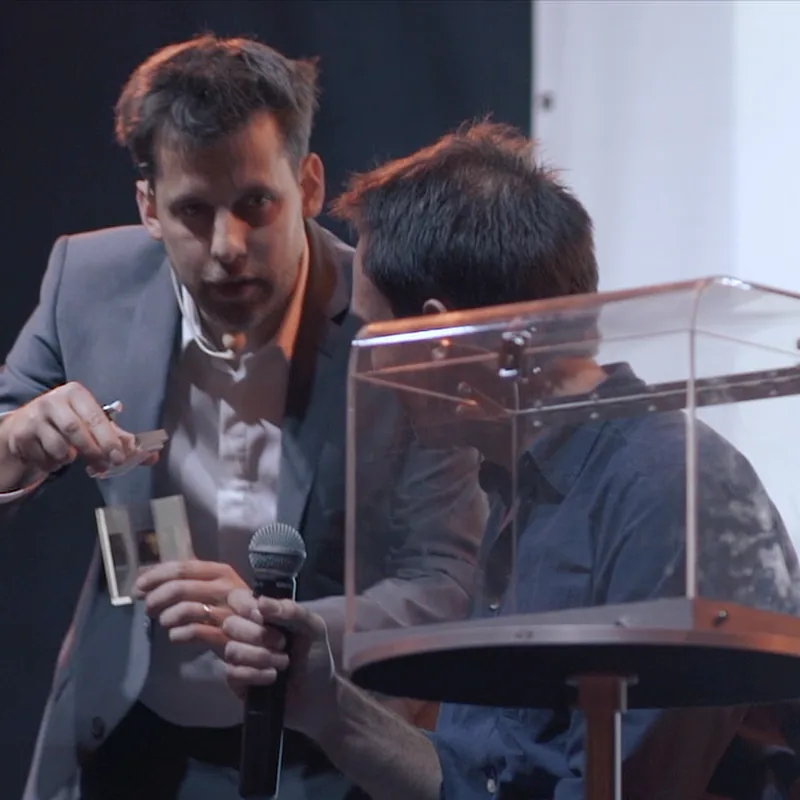 Yves Doumergue sur scène avec un spectateur et une boîte transparente
